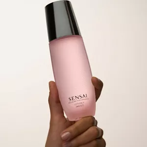 Close up of a hand holding Cellular Performance Lotion 2 (Moist) up in front of a neutral light background